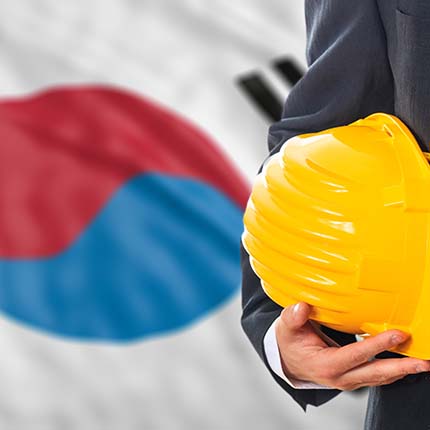 Man in suit with hard hat and Korean flag in background