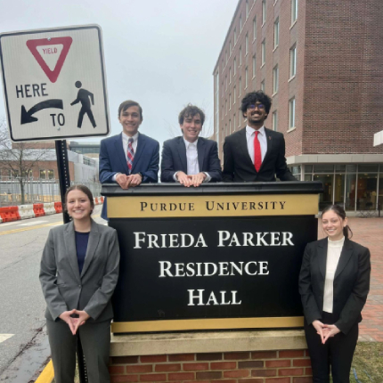 Ryan Mooney and the Frieda Council posing in front of the Frieda Parker Residence Hall sign.